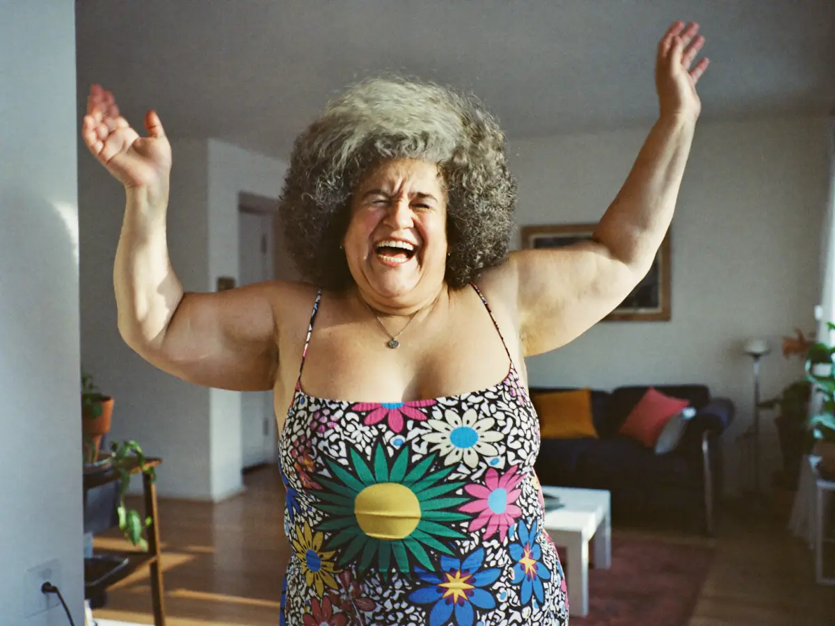 Mulher de 60 anos dançando e rindo na sala de casa